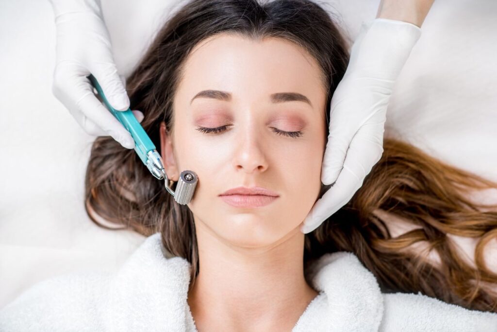 Woman receiving microneedling treatment with a dermaroller on her cheek, performed by a gloved skincare professional in a clinical setting.